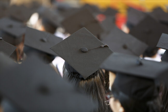 Behind view of graduates at ceremony wearing mortar hats
