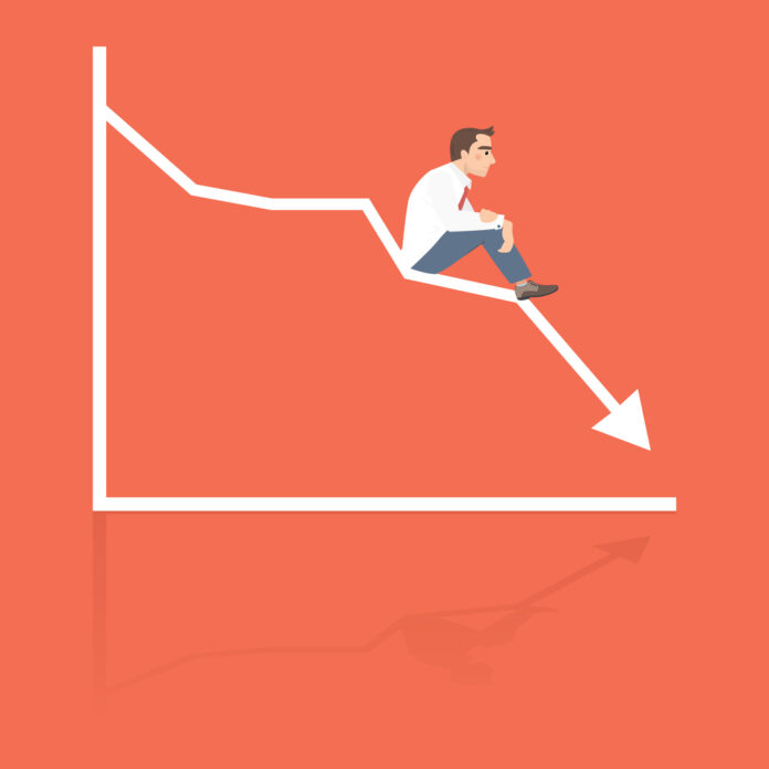Businessman sitting frustratedly on graphic chart
