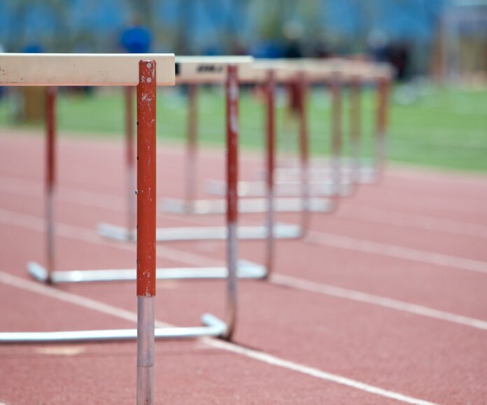 Hurdles lined up on a track, fading focus.