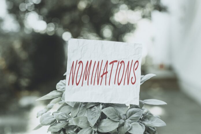Conceptual hand writing showing Nominations. Business photo text action of nominating or state being nominated for prize Plain paper attached to stick and placed in the grassy land.